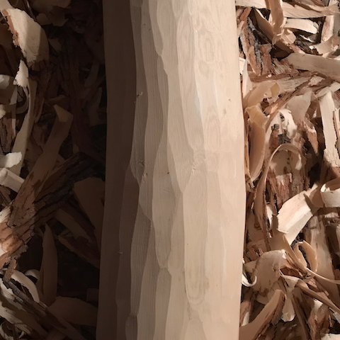 A post carved out of white walnut surrounded by wood shavings